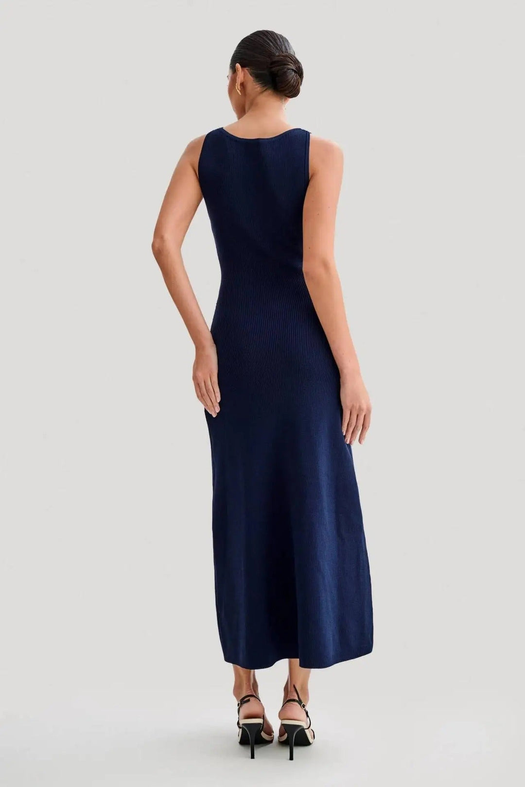 Elegant damekjole uden ærmer i strik, ensfarvet, med knapper foran, kropsnær silhuet, blødt materiale.