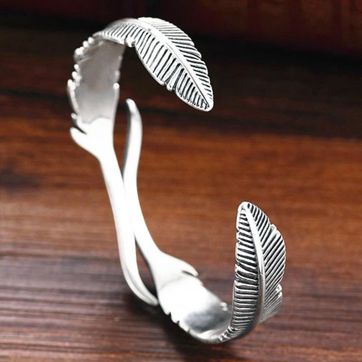 Sølvbelagt dame armbånd med fjerdesign, let og elegant tilbehør der symboliserer beskyttelse og frihed.