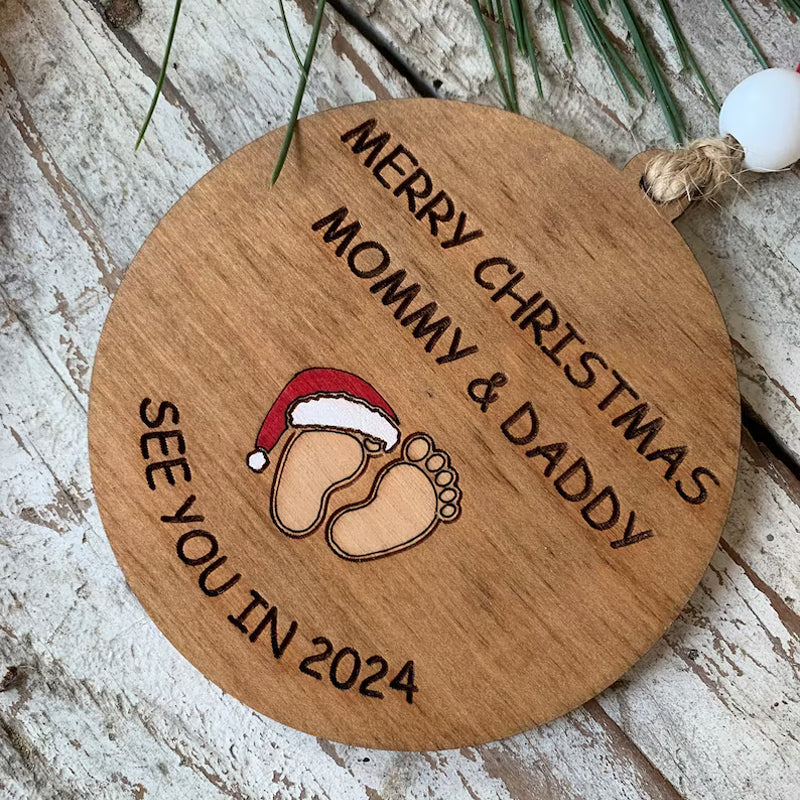 Julepynt til vordende forældre, indgraveret med teksten 'Merry Christmas Mommy and Daddy See You in 2024', bøgetræ