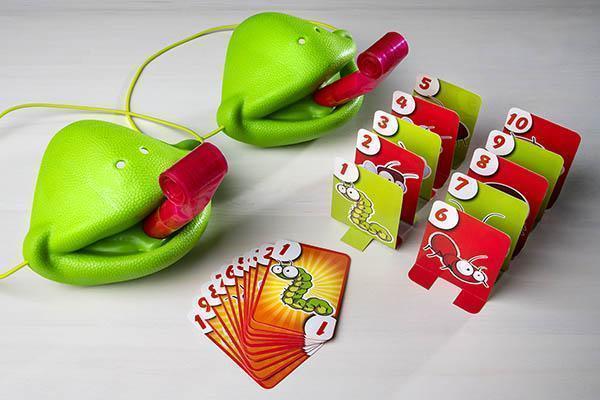Kameleontspil til familien, farverige plastik fuglefigurer og spillekort i en legende opsætning.