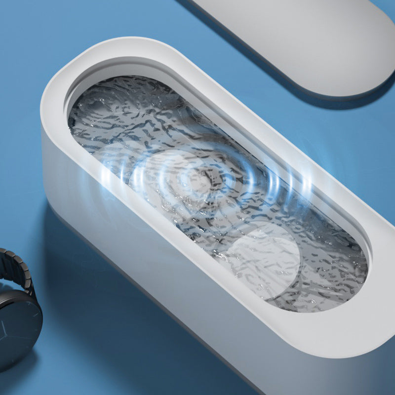 Kompakt hvid-grå ultralyd renser til dybderensning; fjerner snavs fra briller og smykker med højfrekvent vibration