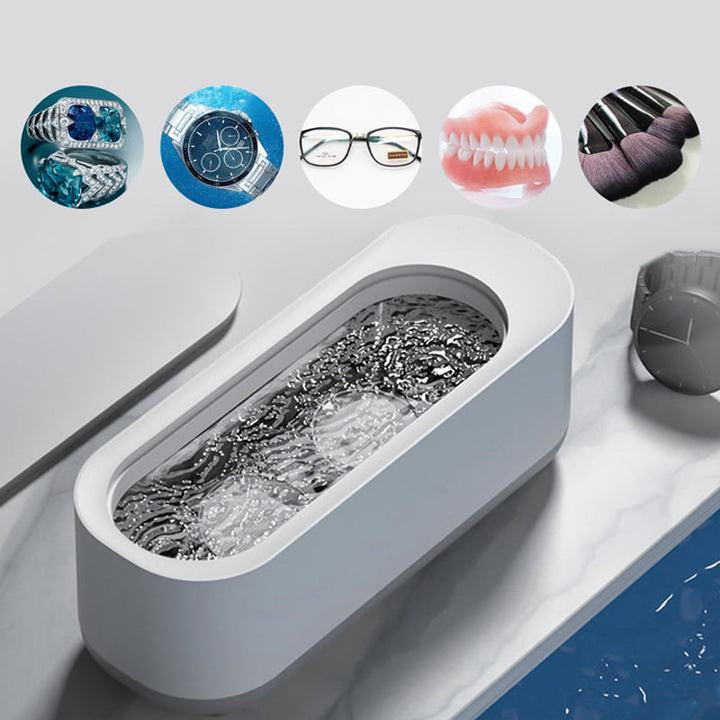 Kompakt hvid-grå ultralyd renser til dybderensning; fjerner snavs fra briller og smykker med højfrekvent vibration
