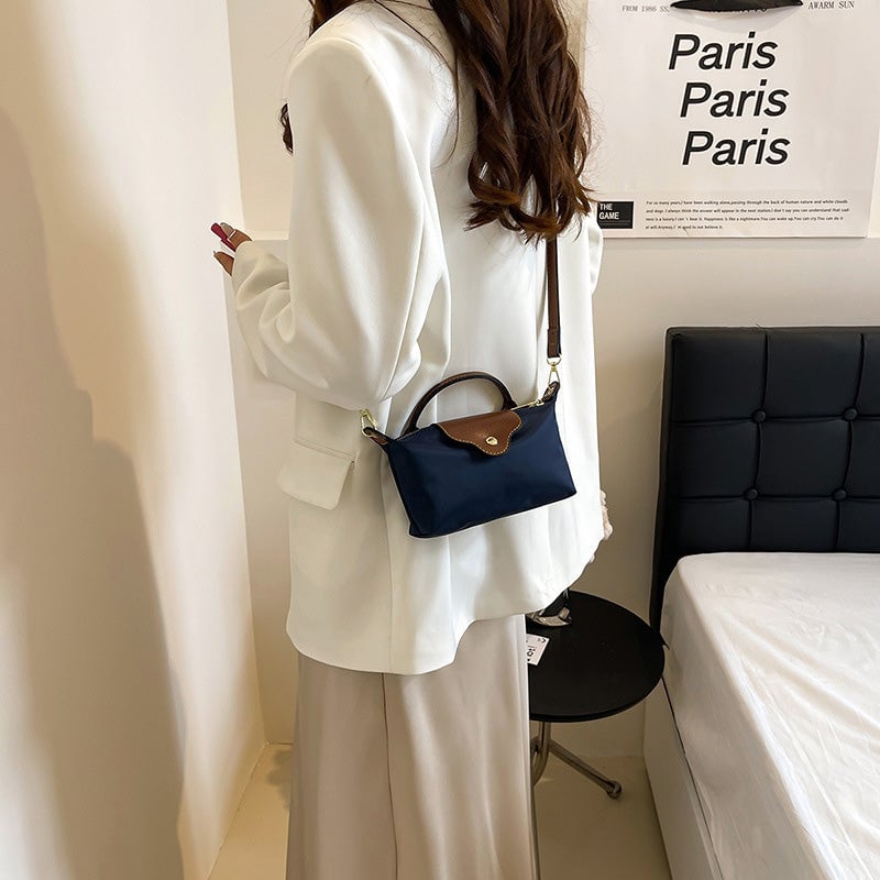 Kompakt farveblok crossbody-taske til damer i nuancer af blå, sort og khaki; en praktisk og stilfuld accessory.