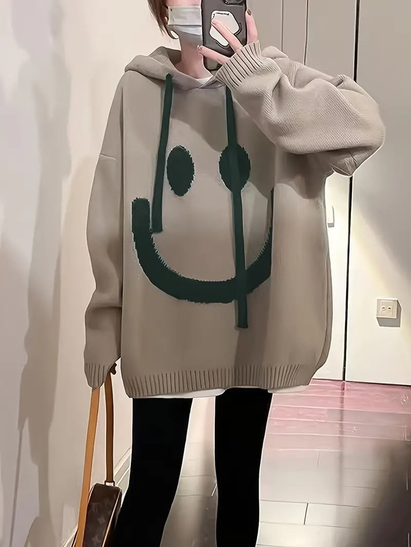 Damehættetrøje med smilende motiv, set forfra, flerfarvet, afslappet og stilfuldt design.