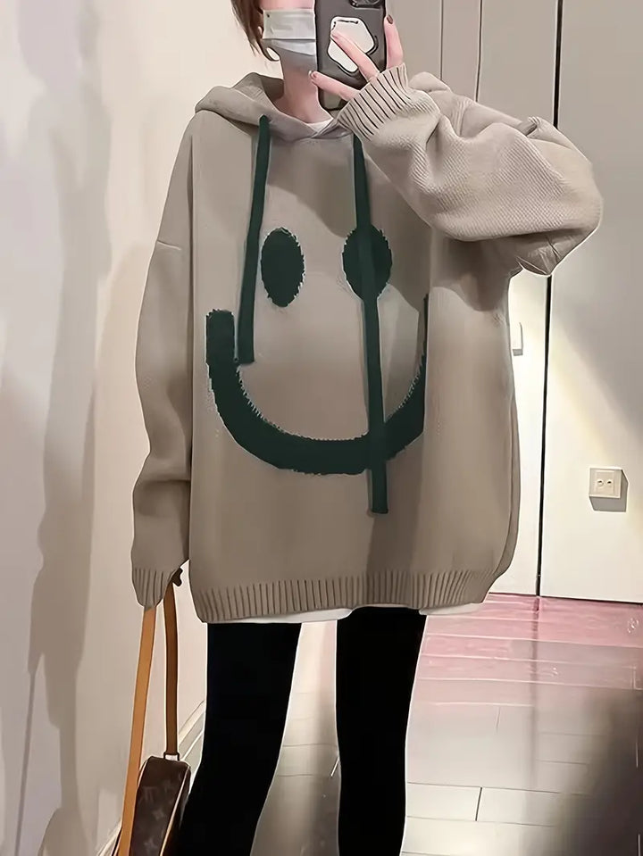 Damehættetrøje med smilende motiv, set forfra, flerfarvet, afslappet og stilfuldt design.