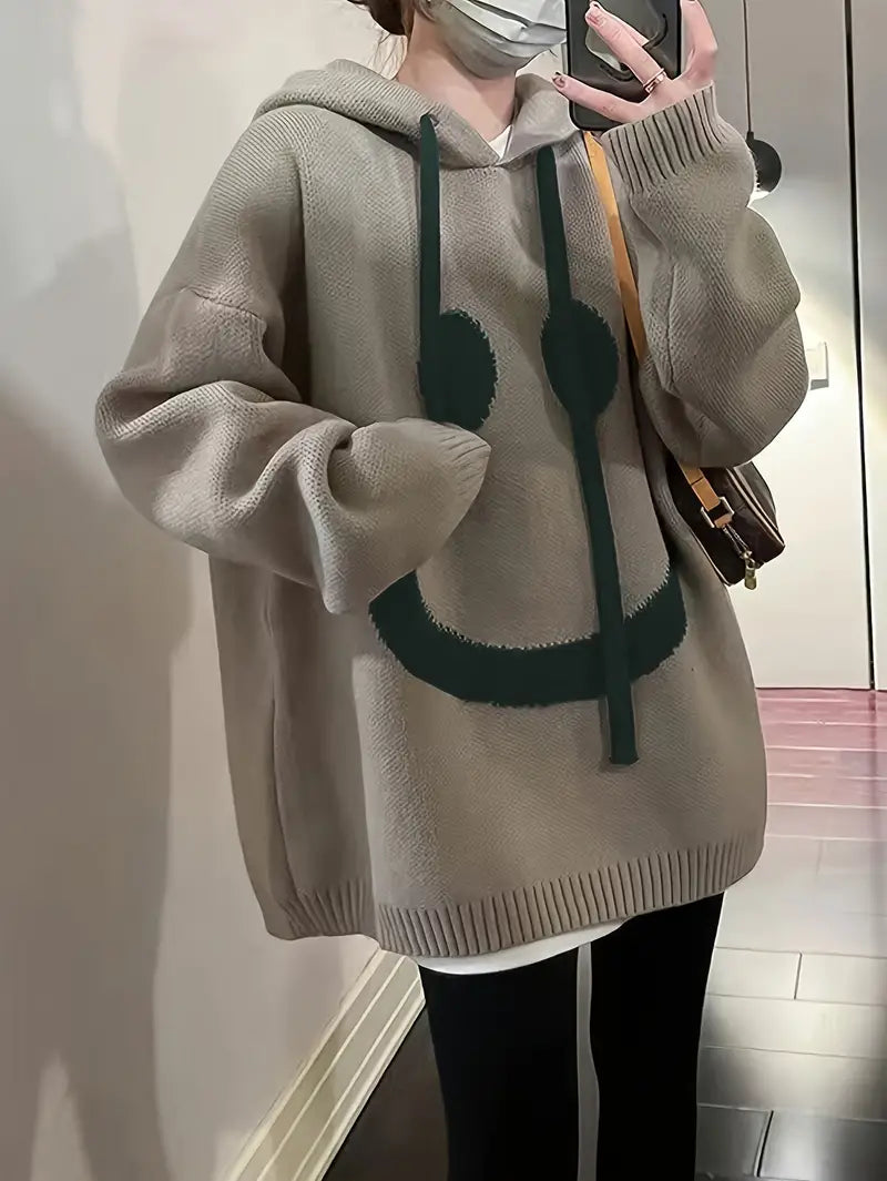 Damehættetrøje med smilende motiv, set forfra, flerfarvet, afslappet og stilfuldt design.