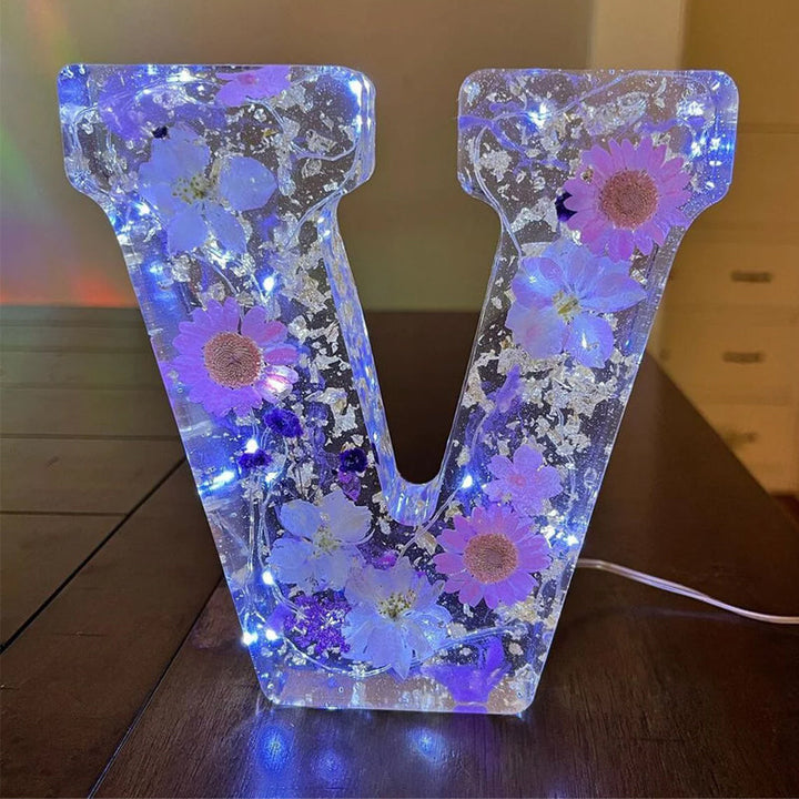 Varm LED natlampe i bogstavsform med tørrede blomster for elegance og romantik i boligindretningen.