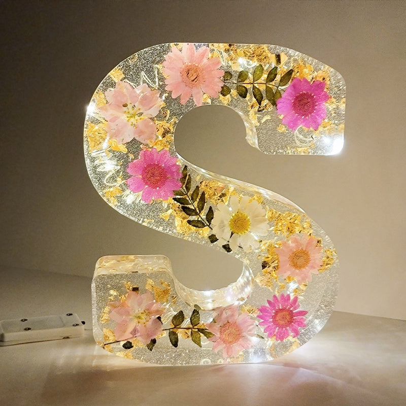 Varm LED natlampe i bogstavsform med tørrede blomster for elegance og romantik i boligindretningen.