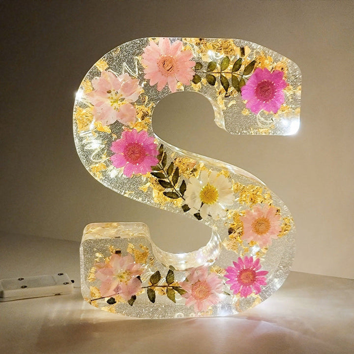 Varm LED natlampe i bogstavsform med tørrede blomster for elegance og romantik i boligindretningen.