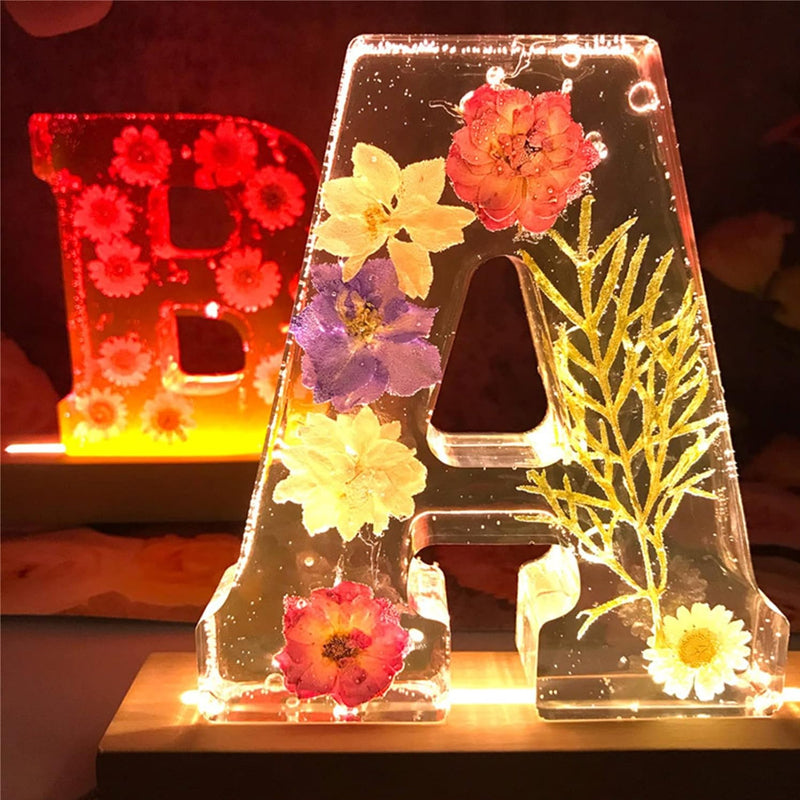 Varm LED natlampe i bogstavsform med tørrede blomster for elegance og romantik i boligindretningen.