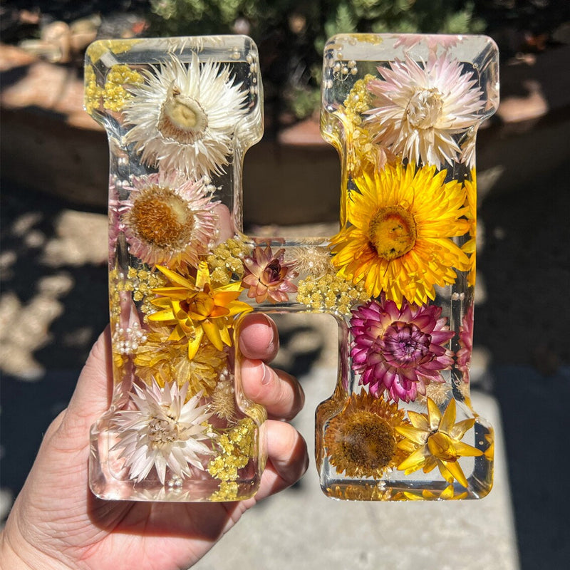 Varm LED natlampe i bogstavsform med tørrede blomster for elegance og romantik i boligindretningen.