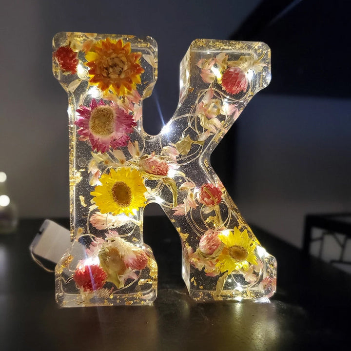 Varm LED natlampe i bogstavsform med tørrede blomster for elegance og romantik i boligindretningen.