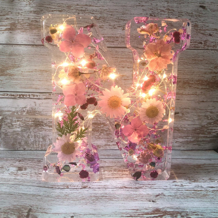 Varm LED natlampe i bogstavsform med tørrede blomster for elegance og romantik i boligindretningen.