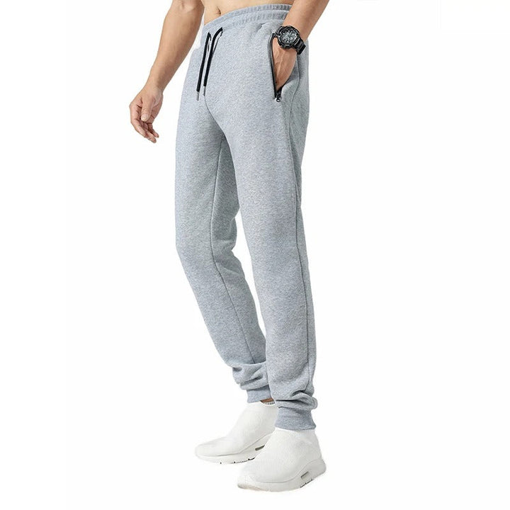 Miesten harmaat loose fit treenijoggerit, joustava vyötärö, vetoketjulliset taskut, hengittävä ja pehmeä kangas.