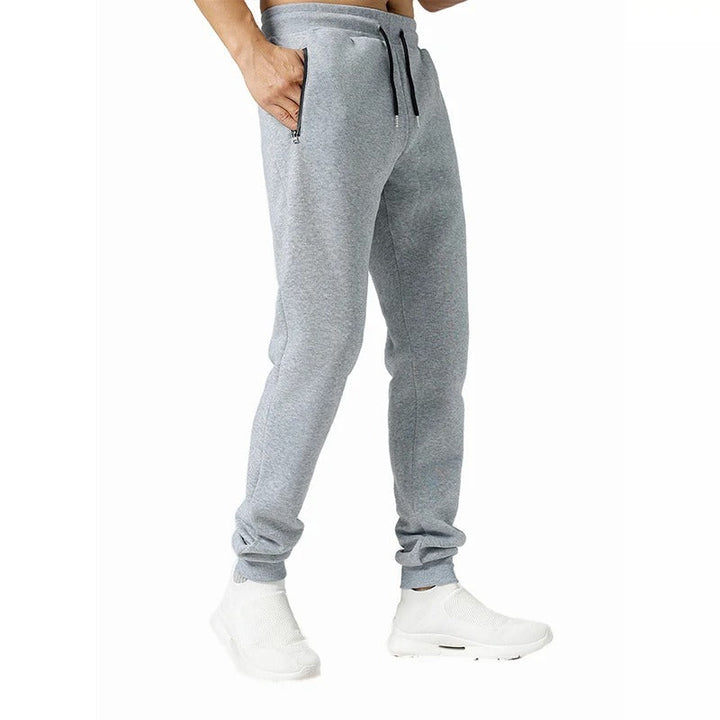 Miesten harmaat loose fit treenijoggerit, joustava vyötärö, vetoketjulliset taskut, hengittävä ja pehmeä kangas.