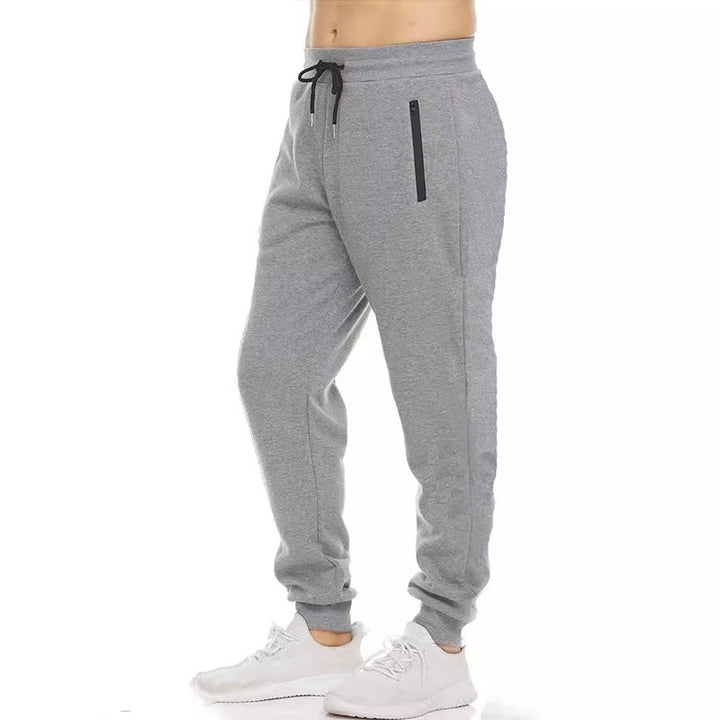 Miesten harmaat loose fit treenijoggerit, joustava vyötärö, vetoketjulliset taskut, hengittävä ja pehmeä kangas.