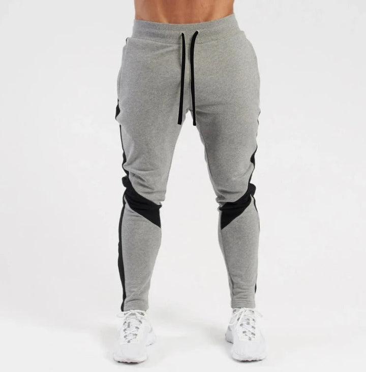 "Miesten hengittävät fitness joggersit, joustava istuvuus, harmaa väri, taskut, kiristysnauha vyötäröllä, moderni design."
