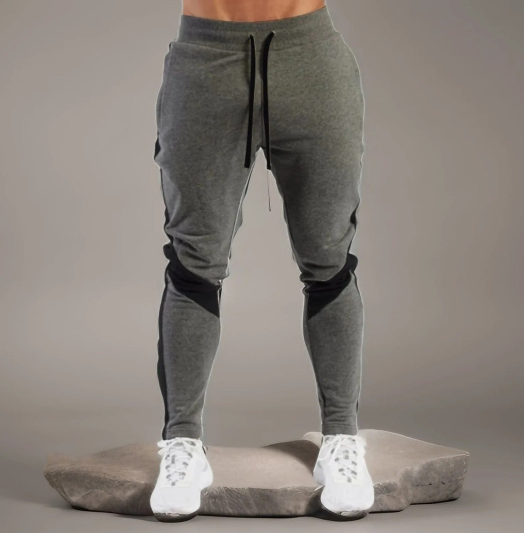 "Miesten hengittävät fitness joggersit, joustava istuvuus, harmaa väri, taskut, kiristysnauha vyötäröllä, moderni design."