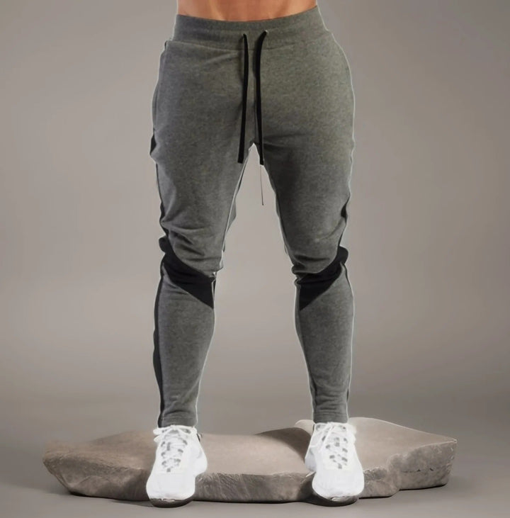 "Miesten hengittävät fitness joggersit, joustava istuvuus, harmaa väri, taskut, kiristysnauha vyötäröllä, moderni design."