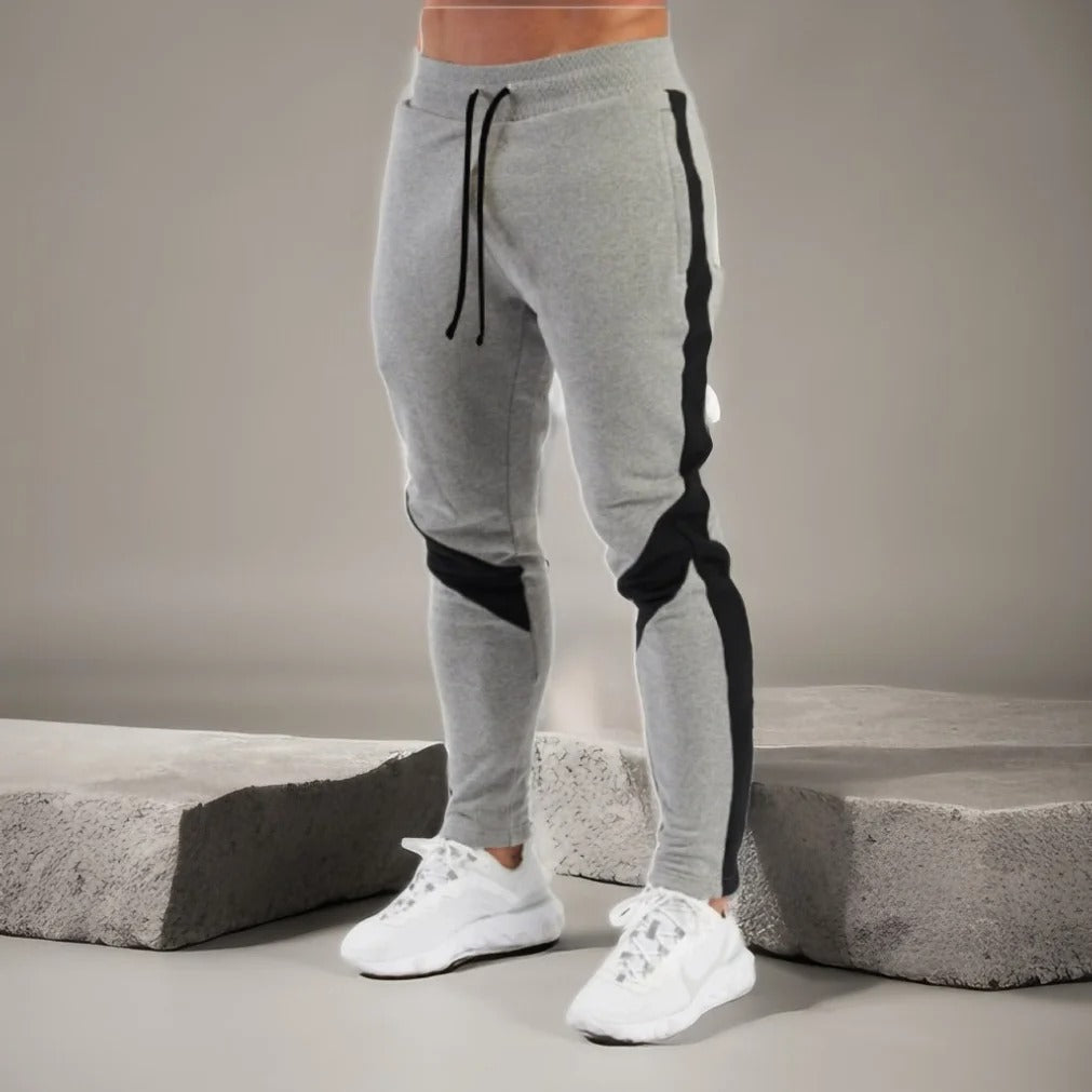 "Miesten hengittävät fitness joggersit, joustava istuvuus, harmaa väri, taskut, kiristysnauha vyötäröllä, moderni design."