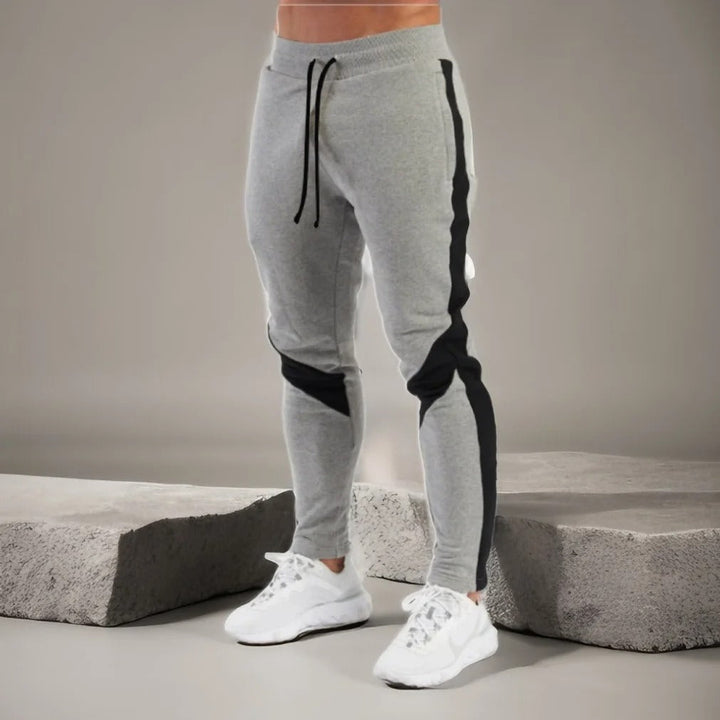 "Miesten hengittävät fitness joggersit, joustava istuvuus, harmaa väri, taskut, kiristysnauha vyötäröllä, moderni design."