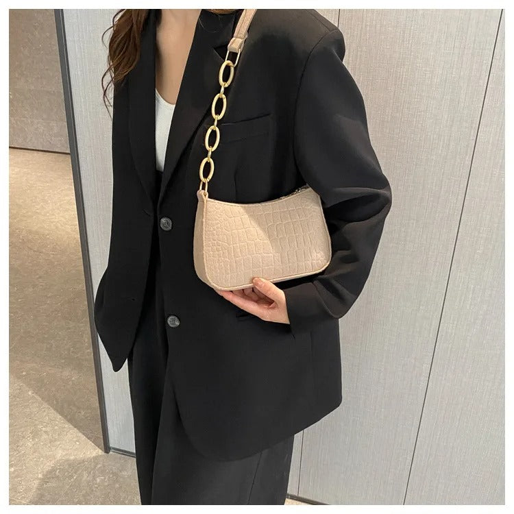 Minimalistisk dame skuldertaske, halvmåneformet top, firkantet bund, grå, kort skulderrem, stilfuld.