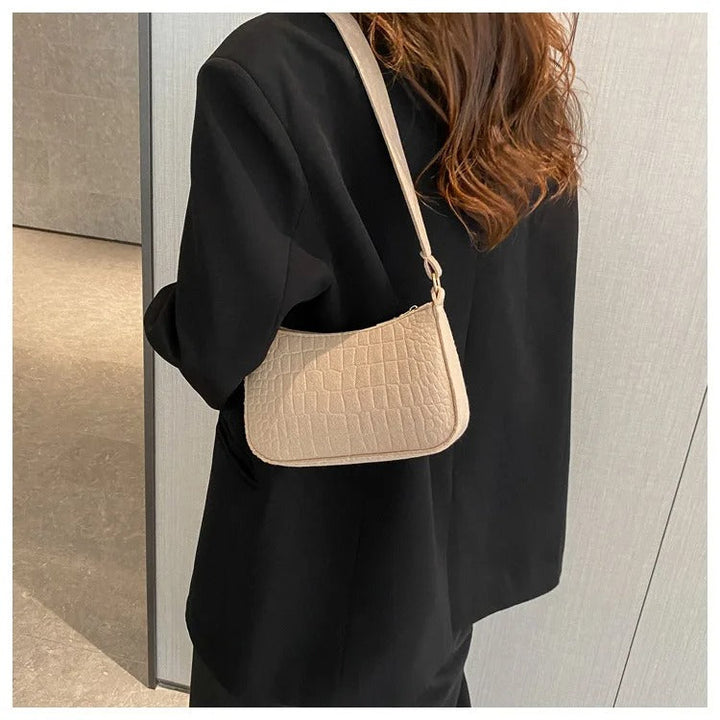 Minimalistisk dame skuldertaske, halvmåneformet top, firkantet bund, grå, kort skulderrem, stilfuld.