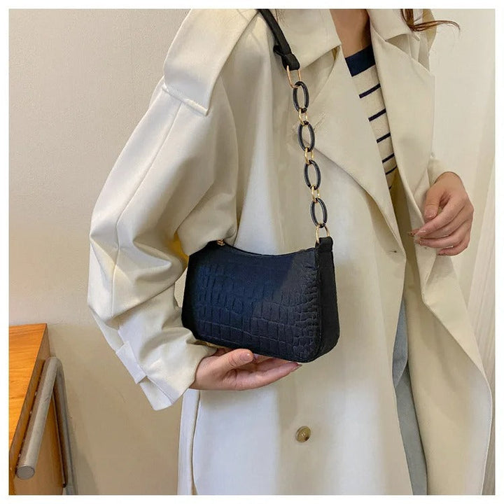 Minimalistisk dame skuldertaske, halvmåneformet top, firkantet bund, grå, kort skulderrem, stilfuld.