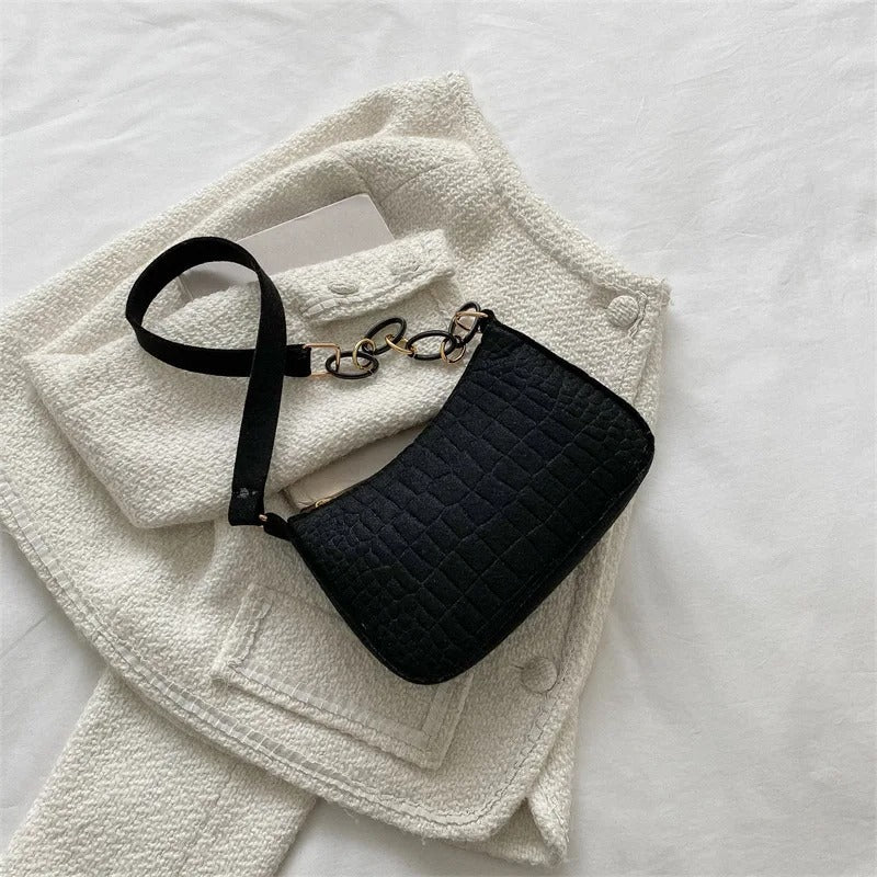 Minimalistisk dame skuldertaske, halvmåneformet top, firkantet bund, grå, kort skulderrem, stilfuld.