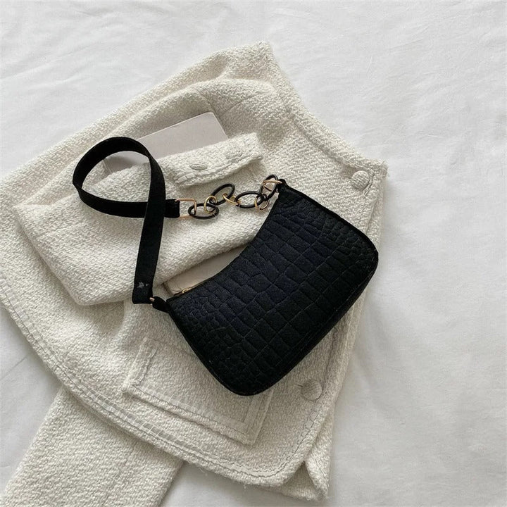 Minimalistisk dame skuldertaske, halvmåneformet top, firkantet bund, grå, kort skulderrem, stilfuld.