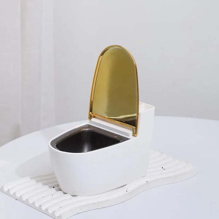 Moderne sølv-guld-hvid toilet askebæger, der ligner et miniaturetoilet, lavet af holdbart ABS-plast.