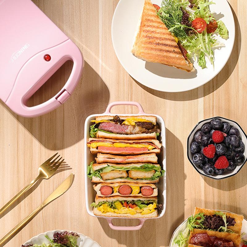 Multifarvet dobbelt smørrebrødgrill, lyserød, rød og grøn, køkkenredskab, kompakt og moderne design.