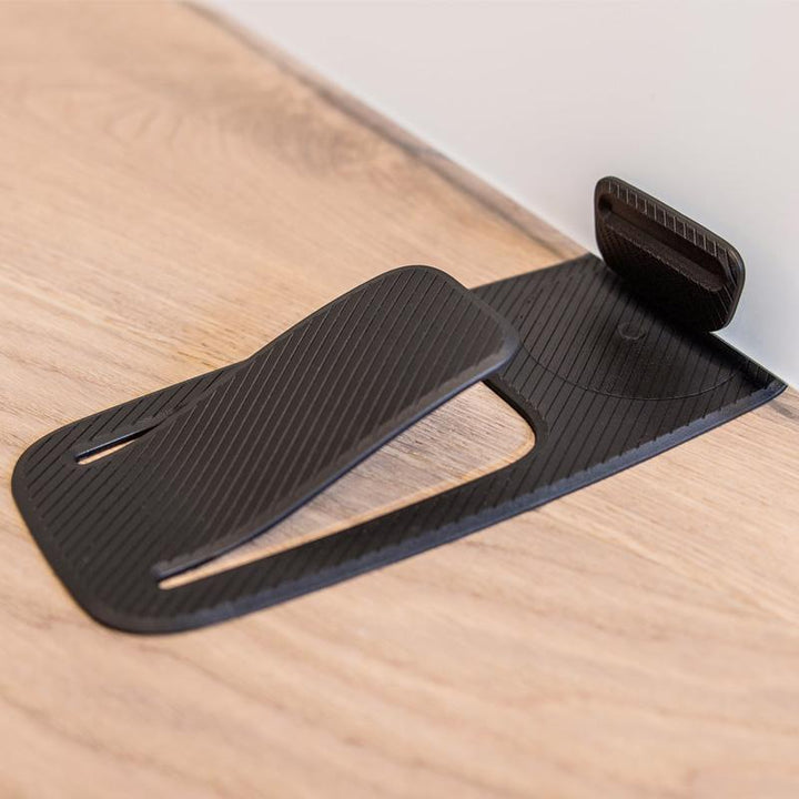Sort dørstopper, kompakt og praktisk design, velegnet til alle overflader, øger dit hjems sikkerhed.