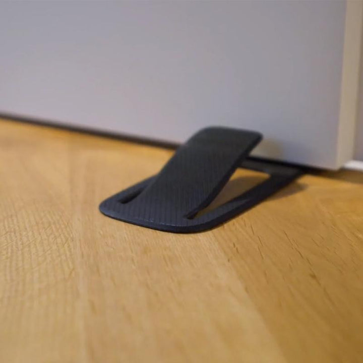 Sort dørstopper, kompakt og praktisk design, velegnet til alle overflader, øger dit hjems sikkerhed.