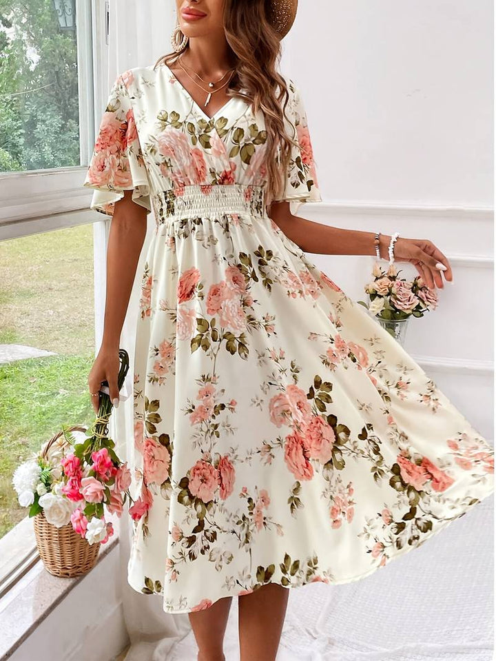 Dame A-formet festkjole med V-hals og blomstertryk, elegant snit og flæseærmer, set forfra.