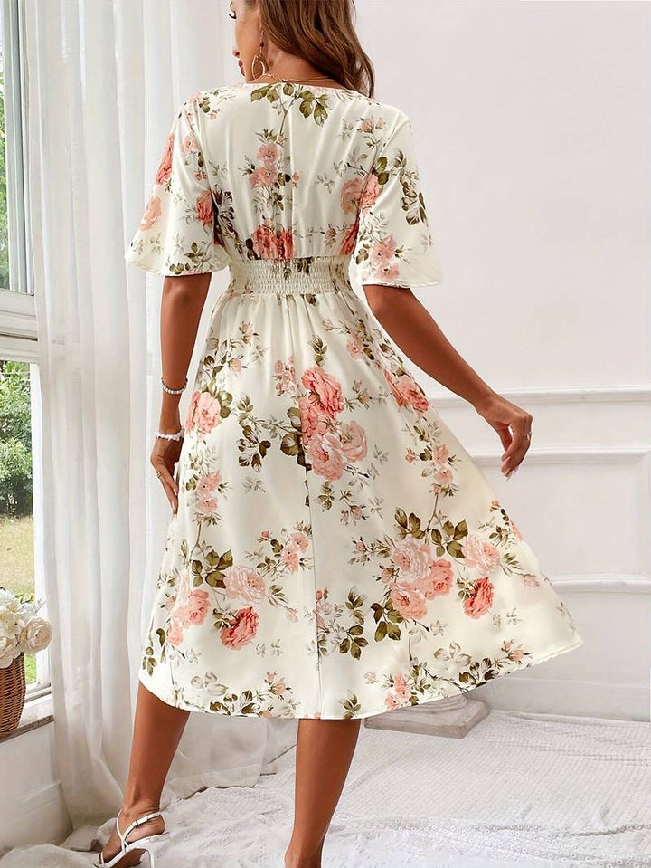 Dame A-formet festkjole med V-hals og blomstertryk, elegant snit og flæseærmer, set forfra.