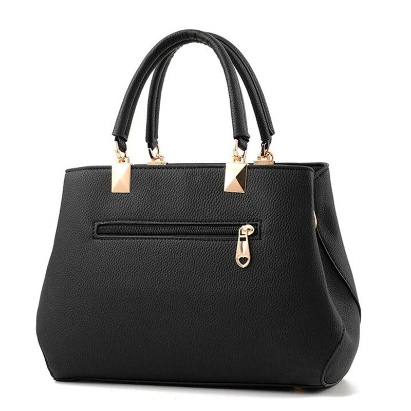 Dame skuldertaske med blomsterhåndtag, struktureret tote-stil, skinnende finish, justerbar rem.