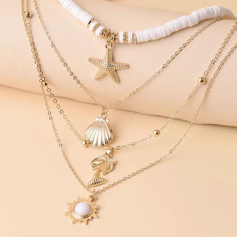 Dame guldfarvet halskæde med flere lag, runde, stjerne- og konkylievedhæng, luksuriøst og stilfuldt design.