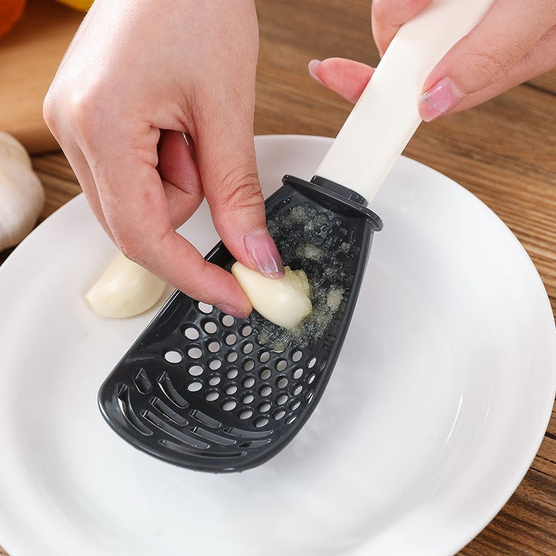 Halvcirkelformet multipurpose ske til køkkenet, rød og grå farve, velegnet til rivning og mosede ingredienser.