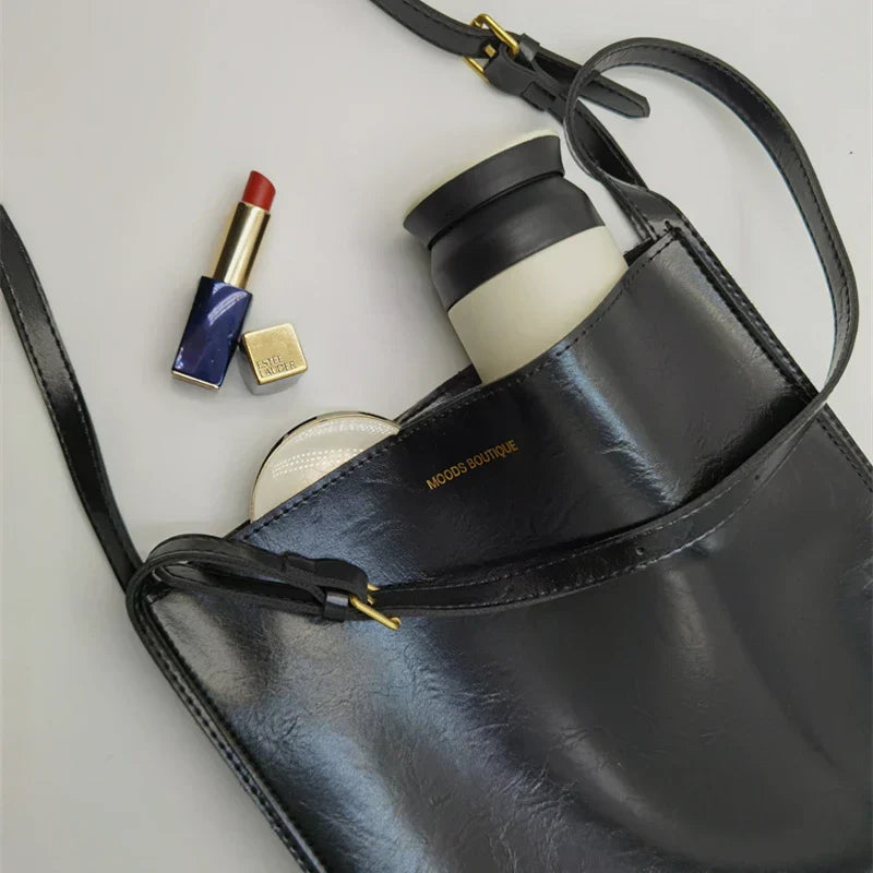 Stilfuld dame skuldertaske i skinnende kunstlæder, rummelig indvendig, justerbar rem, luksuriøst look.