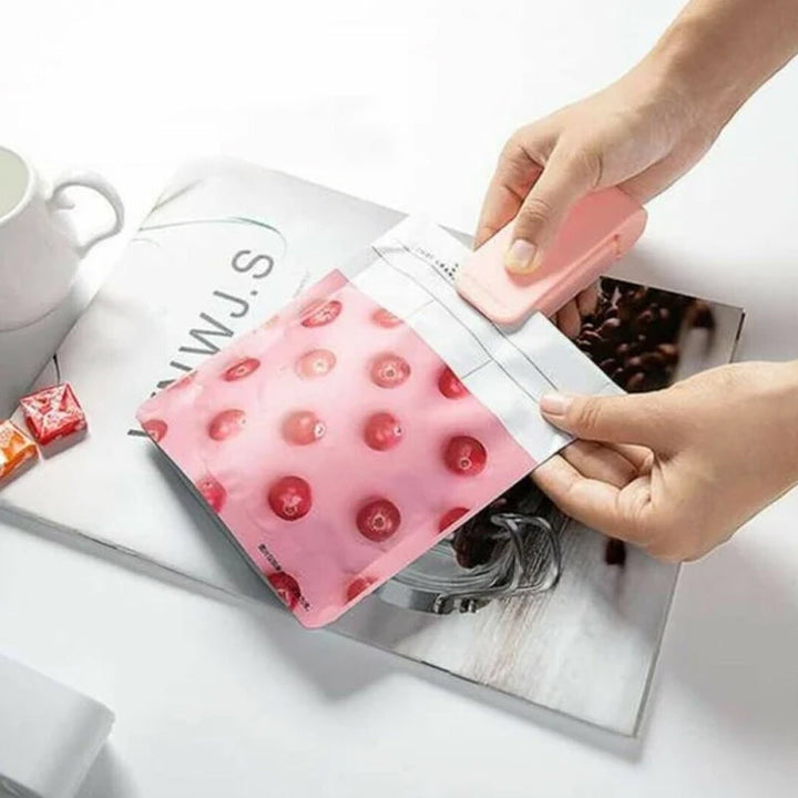 Lyserød håndholdt varmeforseglingsmaskine til fødevareposer, kompakt størrelse med magnetisk fastgørelse.