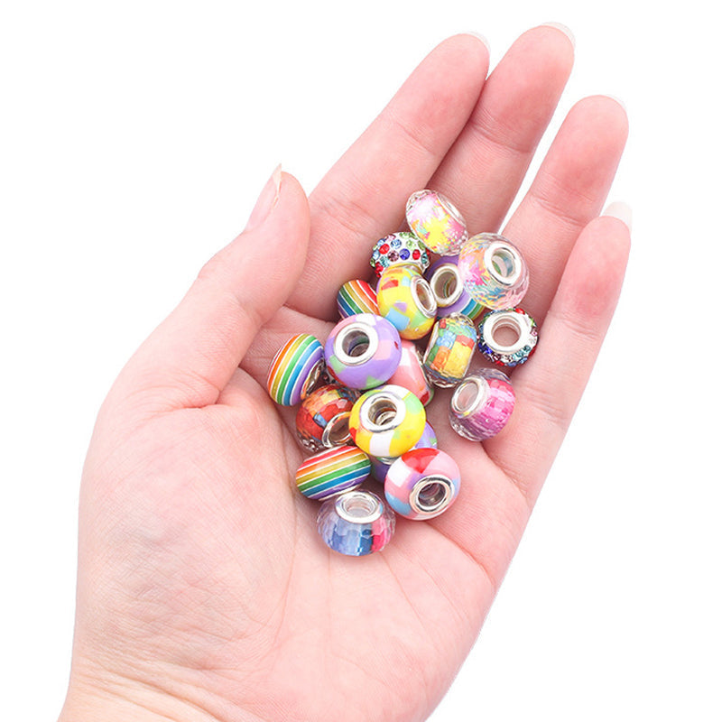 Farverigt DIY-armbåndssæt til børn, indeholder flerfarvede perler og vedhæng til kreative smykkedesigns.