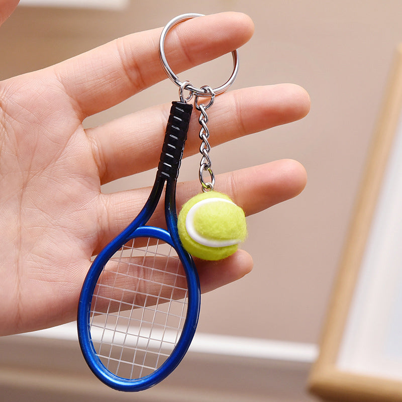 Farverig mini tennisracket nøglering i seks farver: rød, grøn, lilla, sølv, guld og blå.