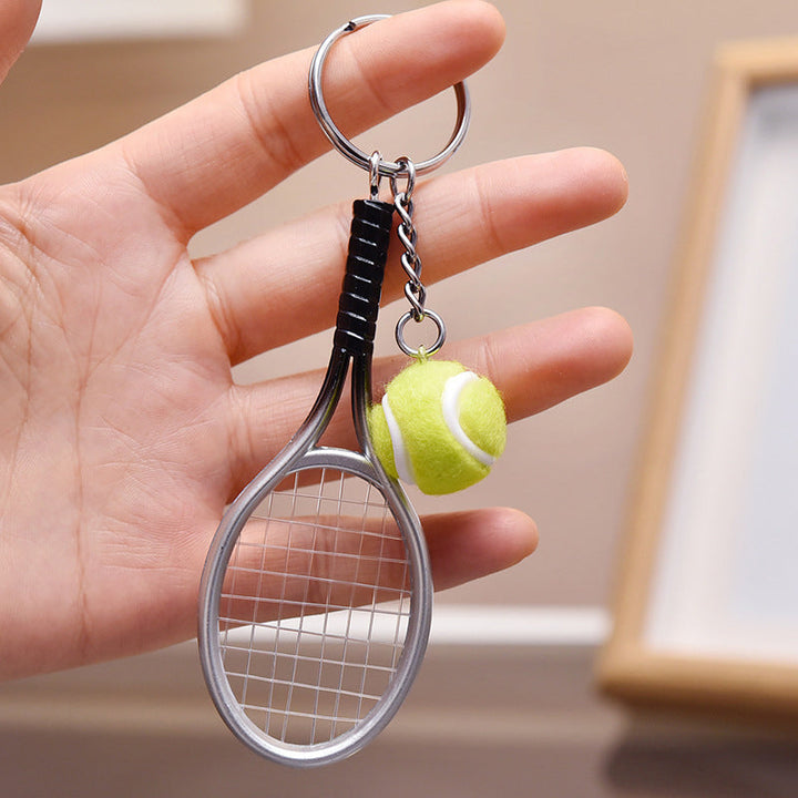 Farverig mini tennisracket nøglering i seks farver: rød, grøn, lilla, sølv, guld og blå.