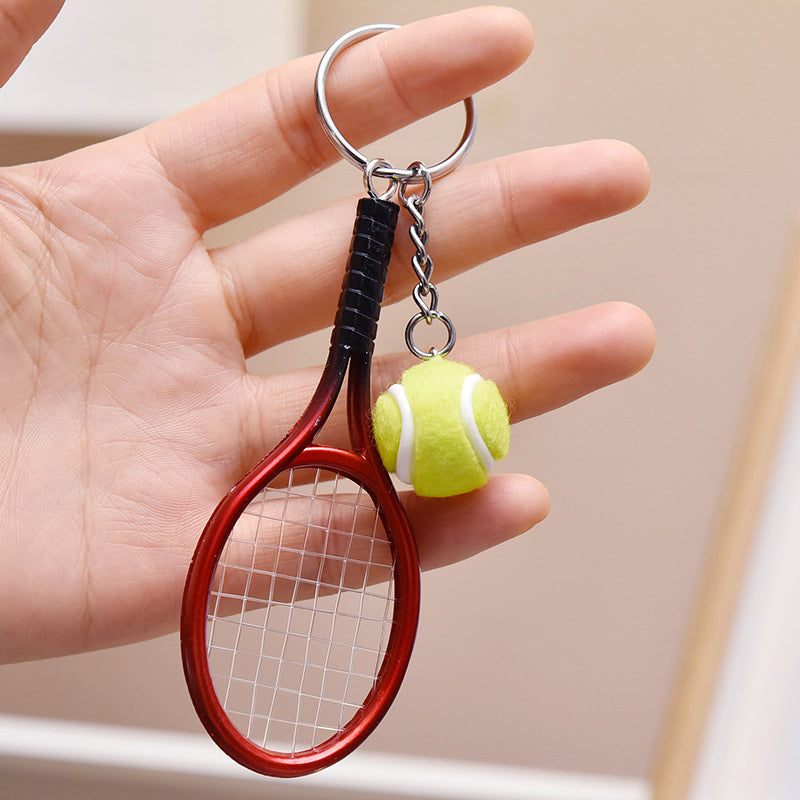 Farverig mini tennisracket nøglering i seks farver: rød, grøn, lilla, sølv, guld og blå.