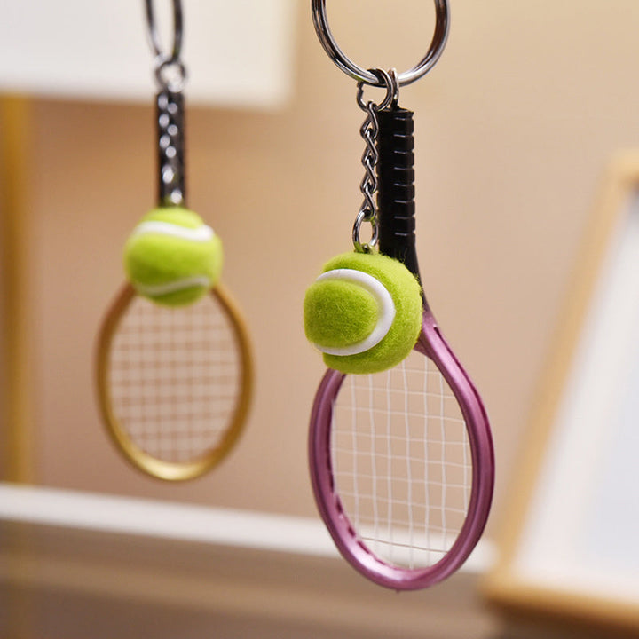Farverig mini tennisracket nøglering i seks farver: rød, grøn, lilla, sølv, guld og blå.