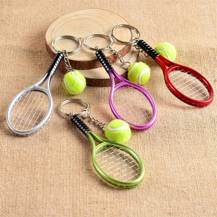 Farverig mini tennisracket nøglering i seks farver: rød, grøn, lilla, sølv, guld og blå.