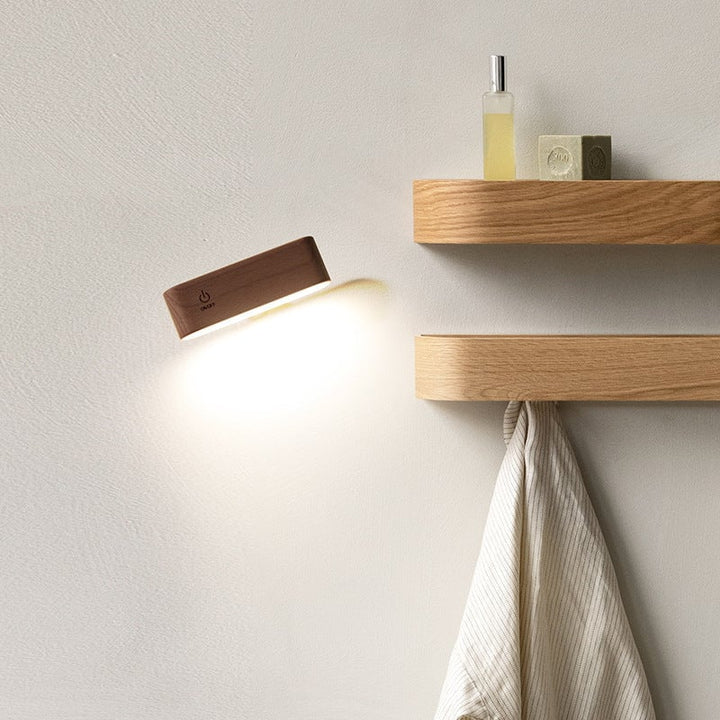 Trådløs GlowBeam væglampe i valnød, med magnetisk holder og 360° rotation for fleksibel belysning.