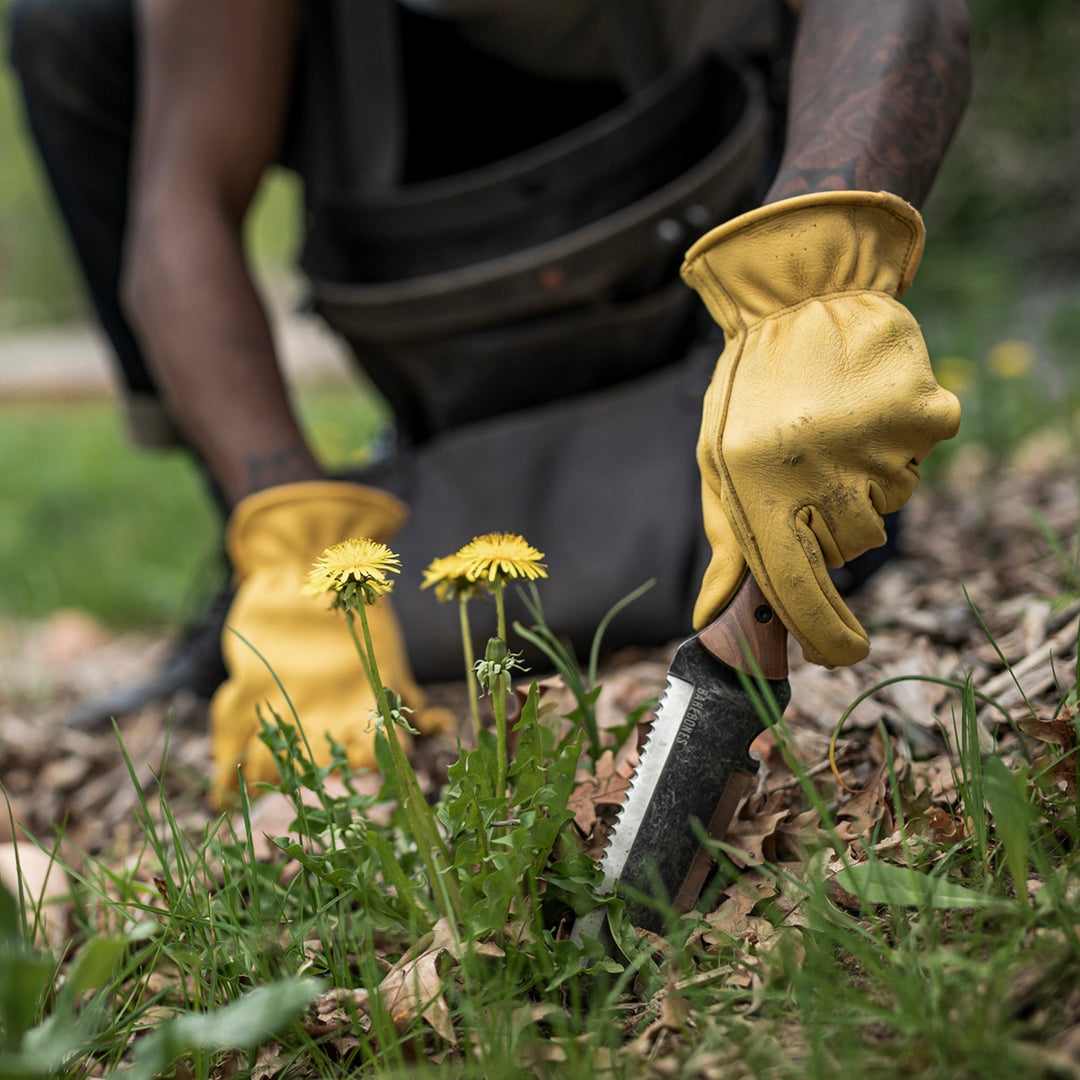 Hori Hori haveværktøj i brug, der graver jord for plantning af en ny blomst.