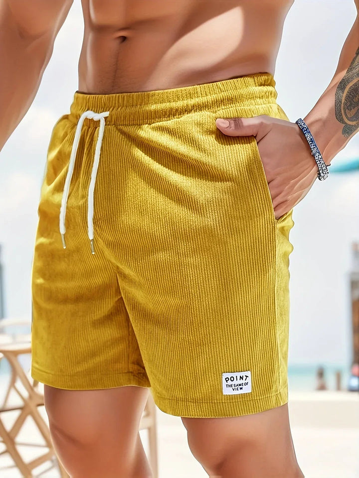 En mand i komfortable stribede shorts, nyder en afslappet sommerdag i stilfuld herremode.